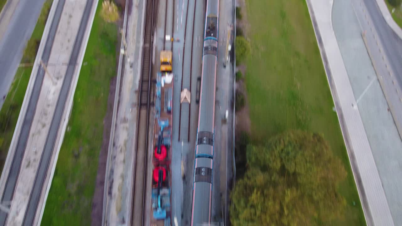 Altından bir trenin geçtiği tren hattının üzerinden uçan drone çekimi.