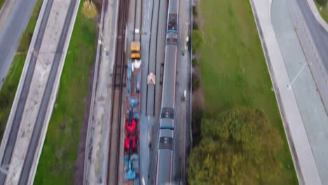 drone shot flying over a train line with a train passing by underneath
