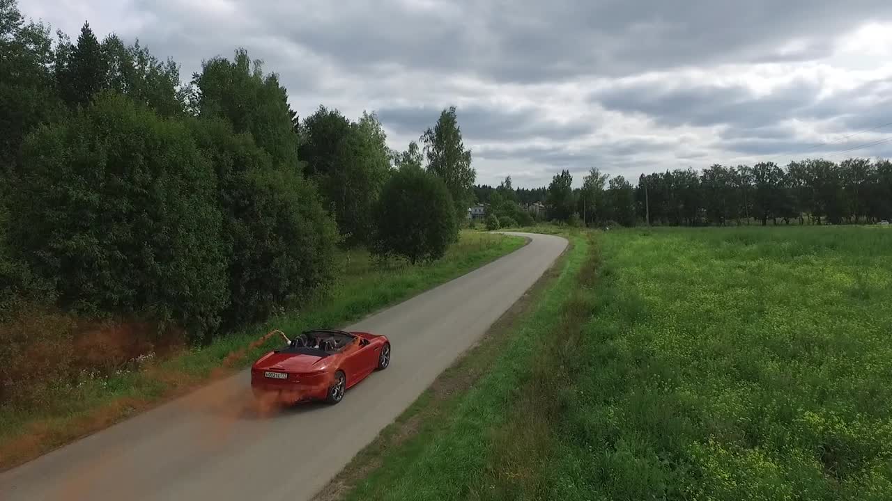 coche rojo conduciendo en una carretera de campo con humo