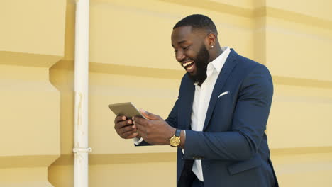 Successful-african-businessman-walking-with-tablet-computer-on-urban-street.