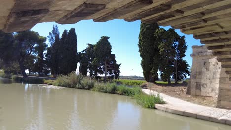 Canal-Du-Midi-reflections-of-the-water-reflect-on-the-underside-of-a-bridge-over-the-canal-early-on-a-warm-September-day