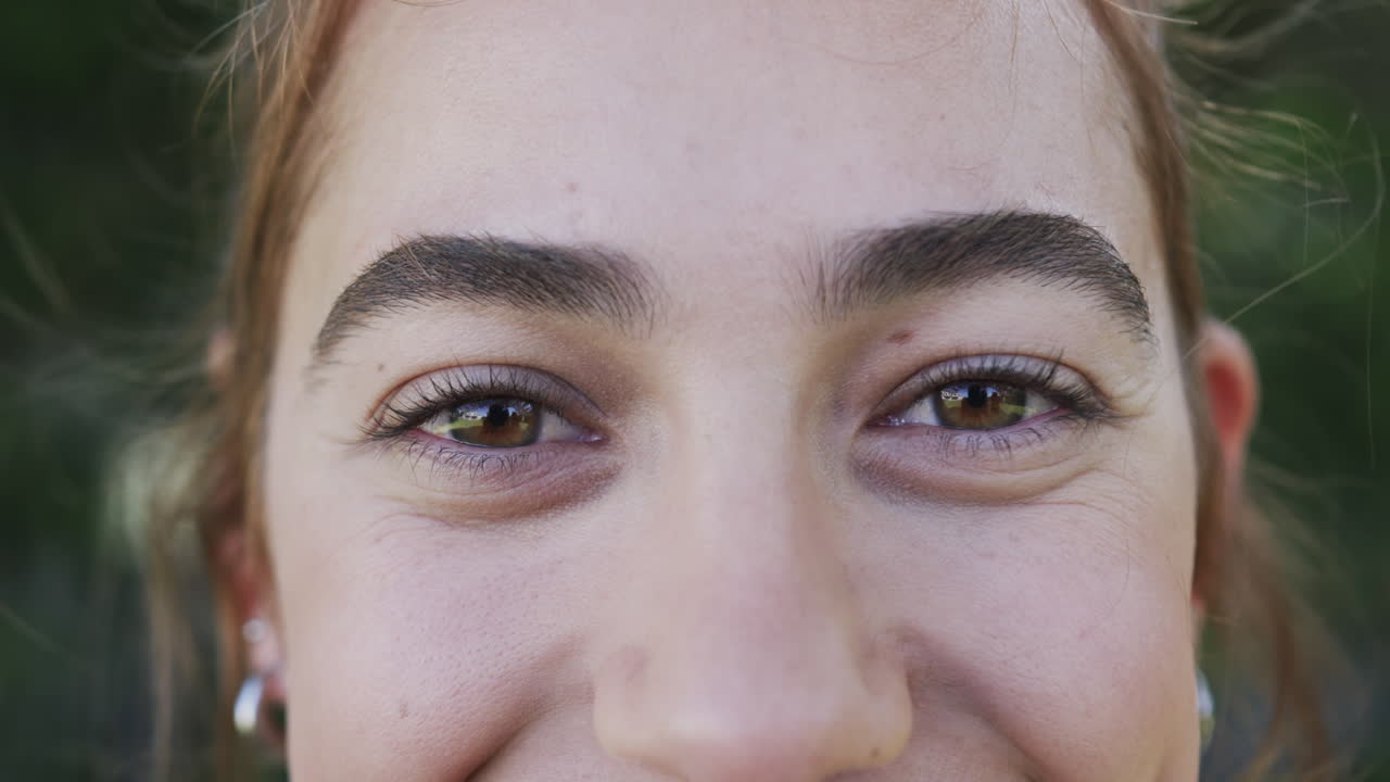 los ojos de una feliz mujer caucásica de pie y sonriendo en un jardín soleado, cámara lenta