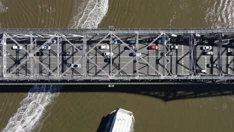 a tourist boat passing under the story bridge a heritage-listed steel cantilever bridge spanning the brisbane river. aerial view