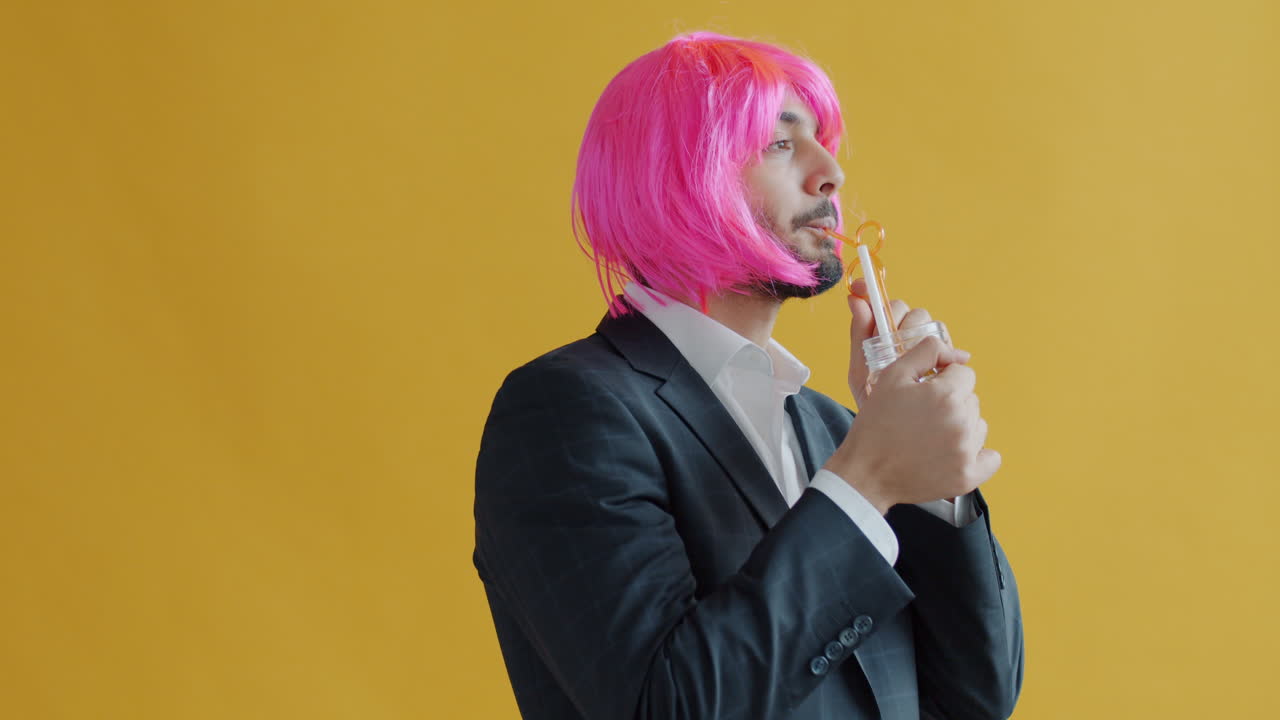 Man in a Suit and Pink Wig Drinking a Cocktail