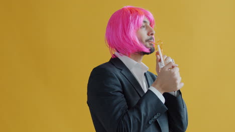man in a suit and pink wig drinking a cocktail