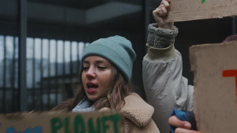 vista ravvicinata di una giovane attivista femminile che tiene un cartello di cartone durante una protesta contro il cambiamento climatico circondata da altri attivisti