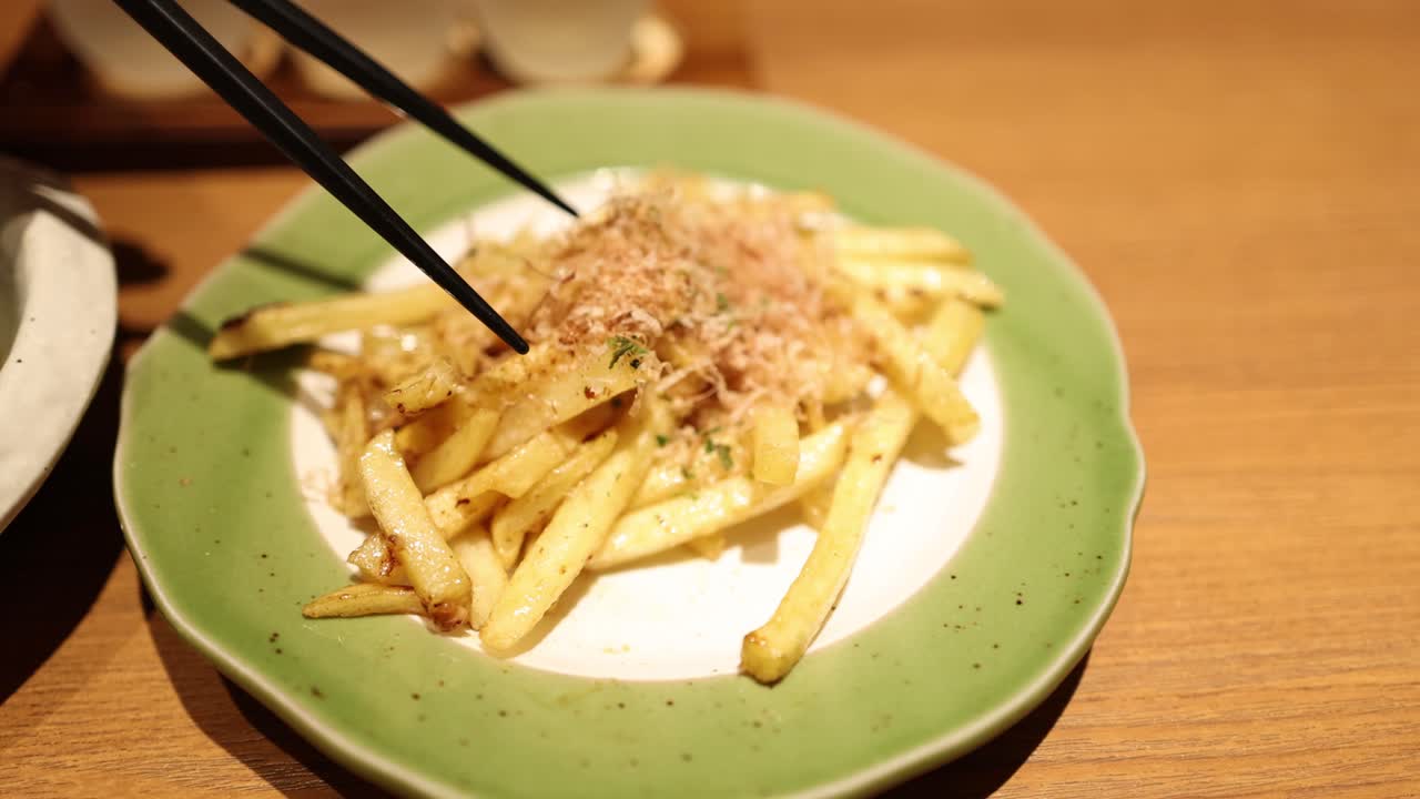 Chopsticks picking up fries from a plate