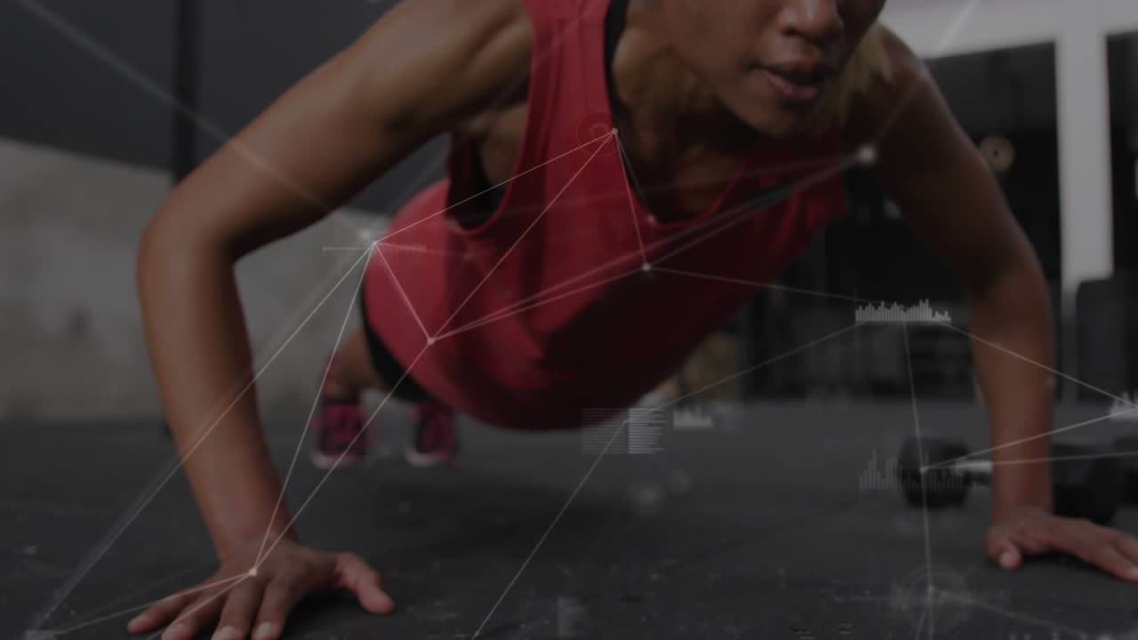 Mid-adult woman starting push-up in gym, performing reps while digital overlays tracking strength