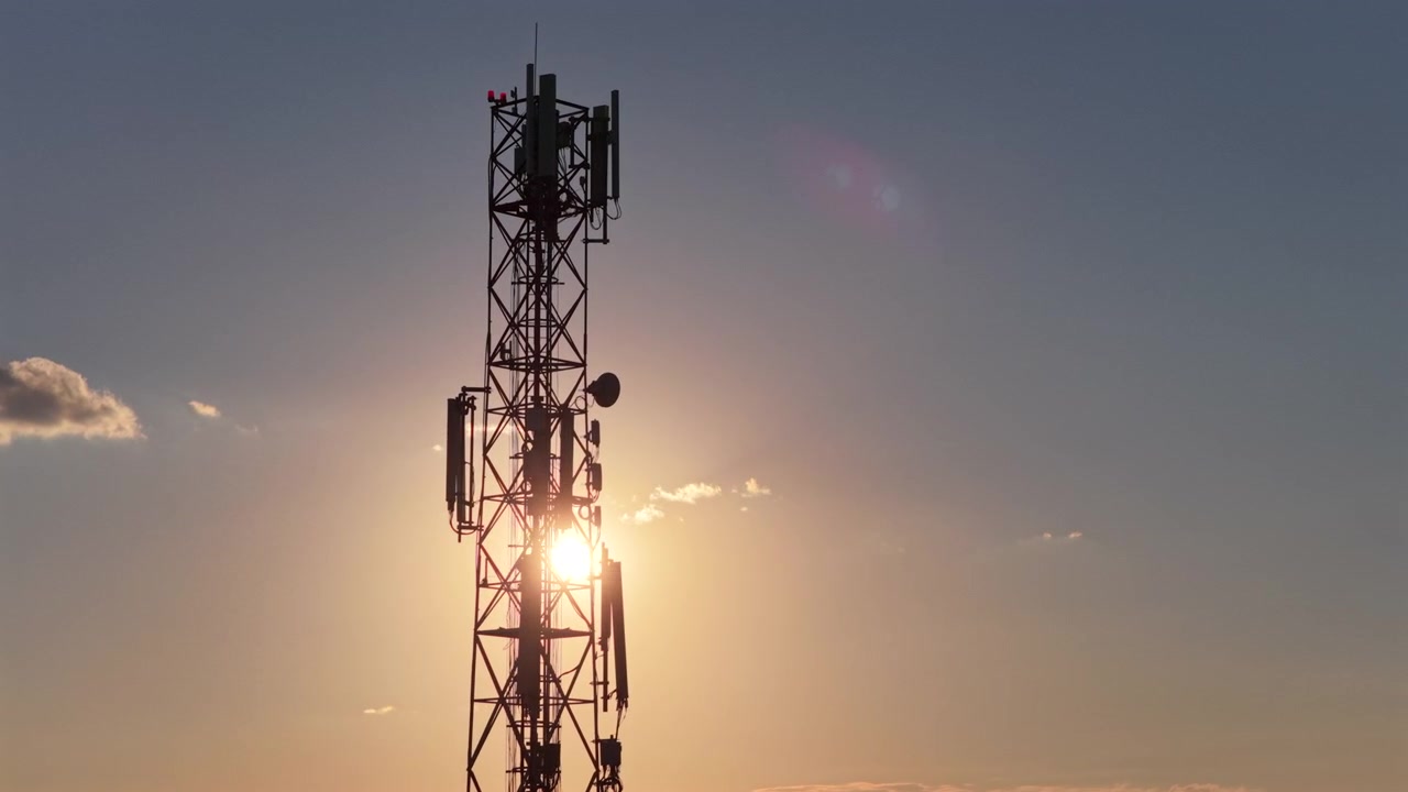 Torre di telecomunicazioni che fornisce connettività, stagliata contro un bellissimo cielo al tramonto con qualche nuvola.