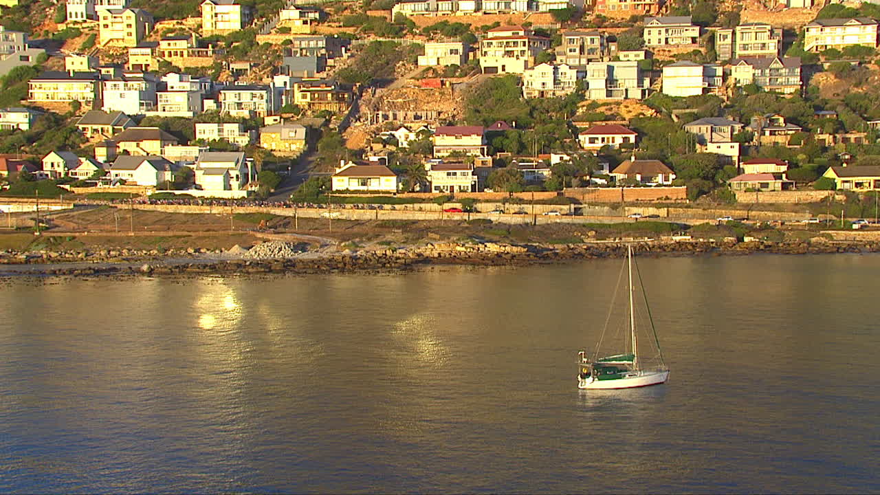 Cyclists going through Fish Hoek. Yacht in the foreground.