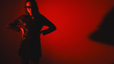 stylish woman in a sequined dress under red light