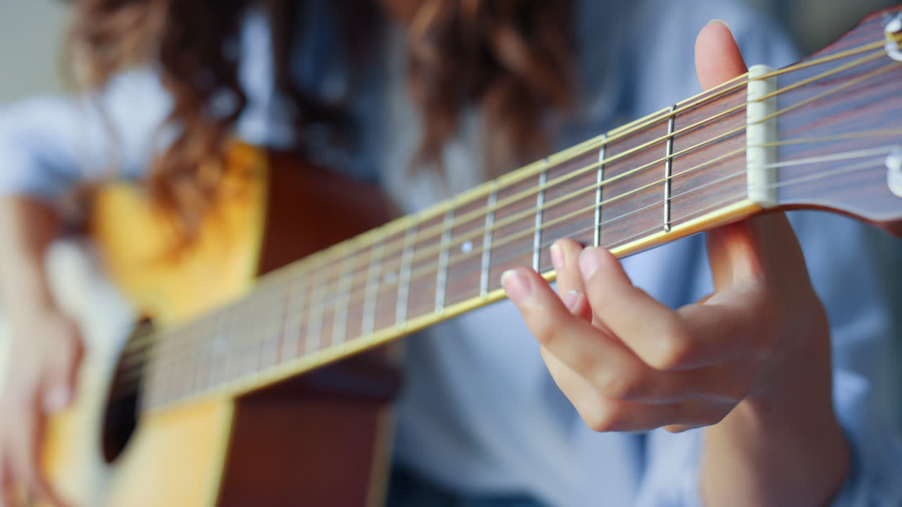 manos de mujer tocando guitarra acústica. niña adolescente creando una canción con guitarra