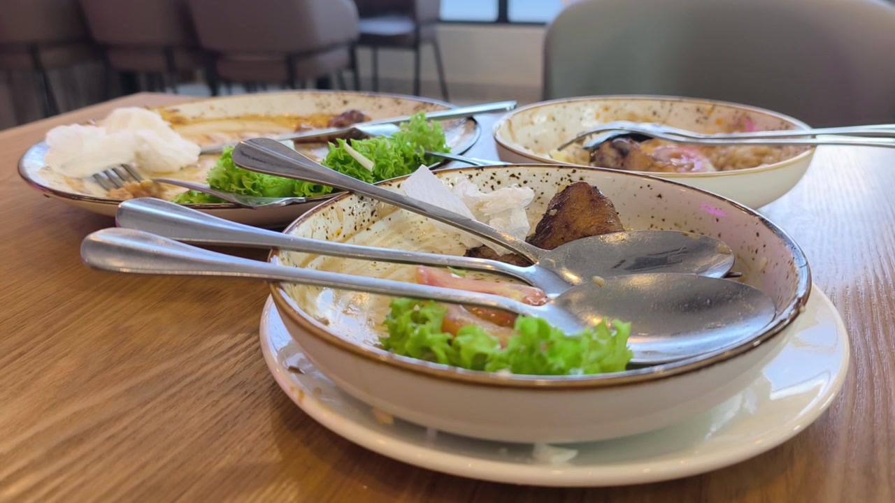 Diversi piatti sono su un tavolo da pranzo. Il cibo servito è stato completamente consumato. Solo avanzi disordinati e scarti di cibo rimangono sparsi sui piatti vuoti