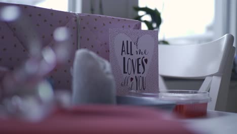 close up of gift focus pulled to a love card, handheld shallow depth of field