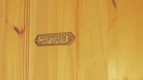 brass metal captain sign mounted on wooden door