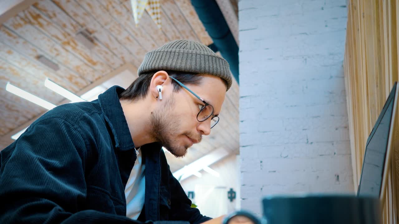 el tipo de las gafas está escribiendo en el teclado y escribiendo con una pluma. trabajo de oficina.