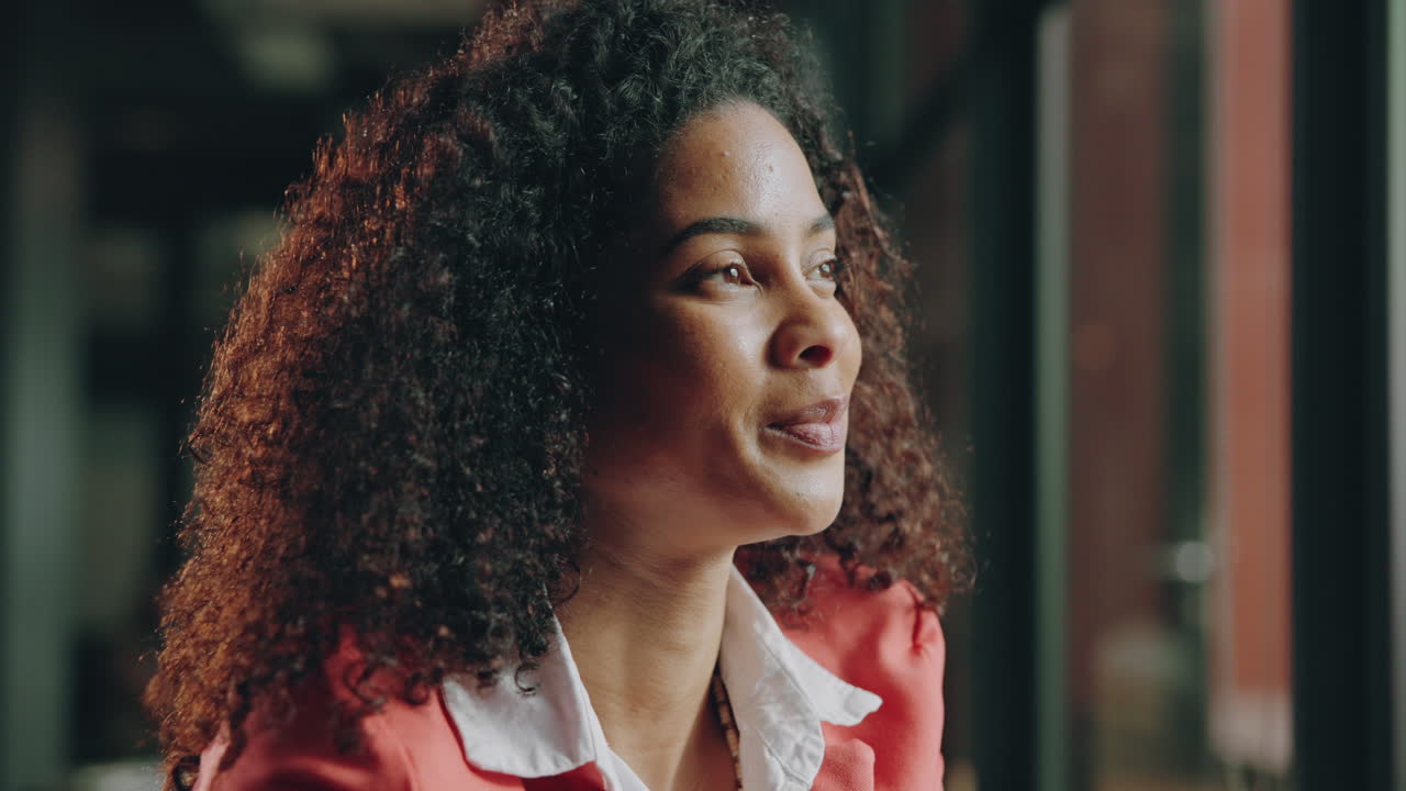 Woman with curly hair smiling and looking out a window