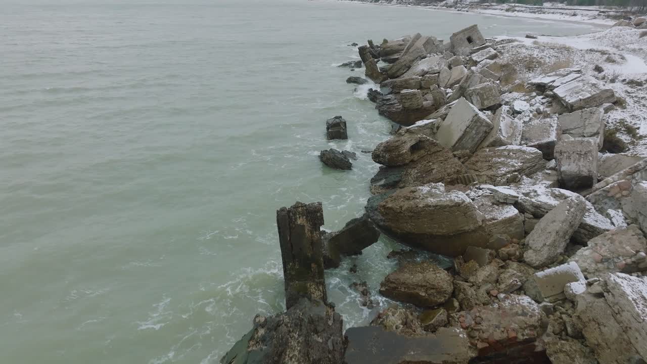 вид с высоты птичьего полета на заброшенные приморские фортификационные сооружения в северных фортах каросты на берегу балтийского моря, пасмурный зимний день, съемка с беспилотника, движущегося вперед