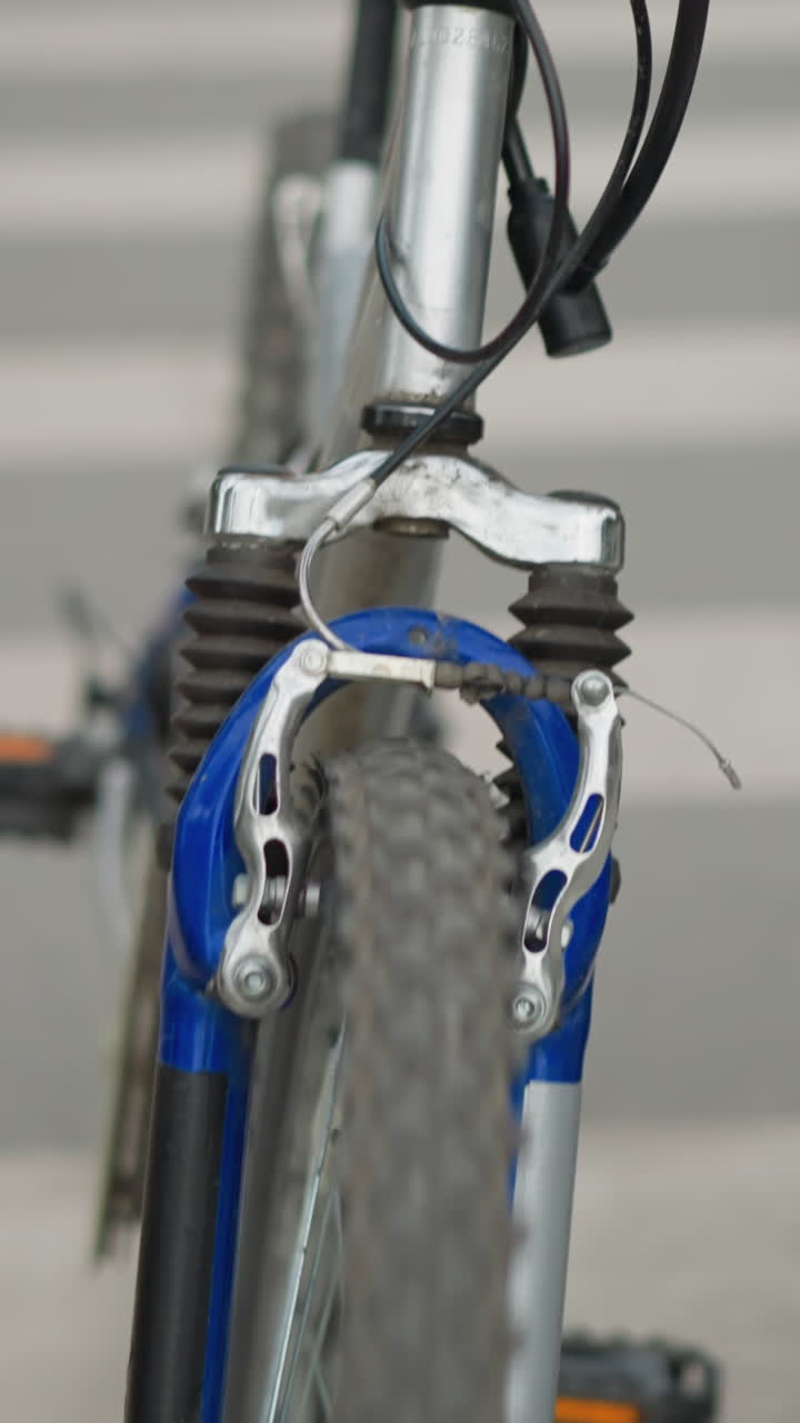 보행자 교차로를 가로질러 자전거와 함께 고 있는 사람의 부분적인 시각의 클로즈업, 은 자전거의 앞 바와 포크에 초점을 맞추고 있습니다.