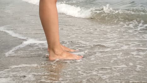 waves breaking over ladies feet