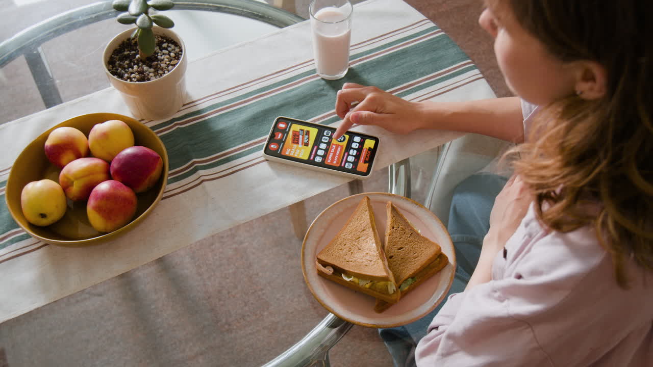 Overhead shot of a person using a phone at a table with food