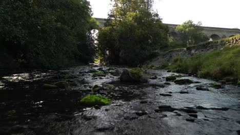 Balbuceo-De-Brook-Drone-Paso-Elevado-Bajo-En-Cámara-Lenta,-Acercamiento-Al-Acueducto-De-Chirk---Río-Ceiriog,-Chirk,-Gales-Reino-Unido---Brumosa-Tarde-De-Verano---23-De-Septiembre