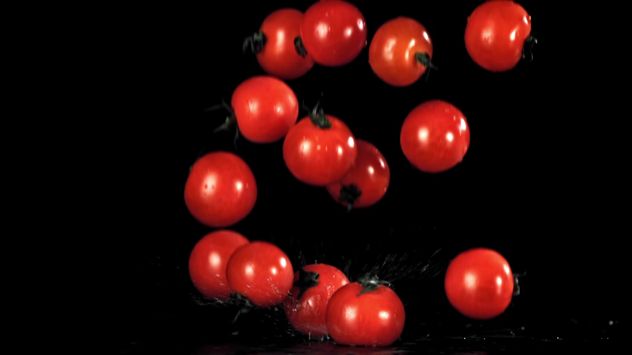 Tomates cherry frescos cayendo y salpicando a cámara lenta