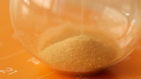 close-up of a sand hourglass on an orange surface