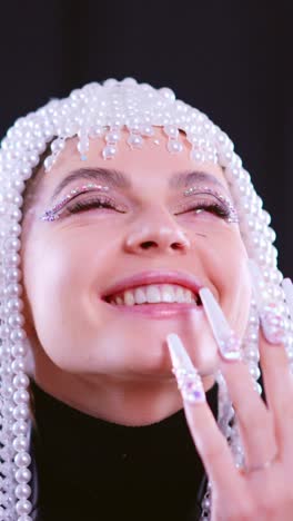 close-up portrait of a woman with a pearl headpiece, glitter makeup, and long decorated nails