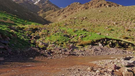 Small-car-drives-on-wild-road-in-High-Atlas-mountains,-Morocco