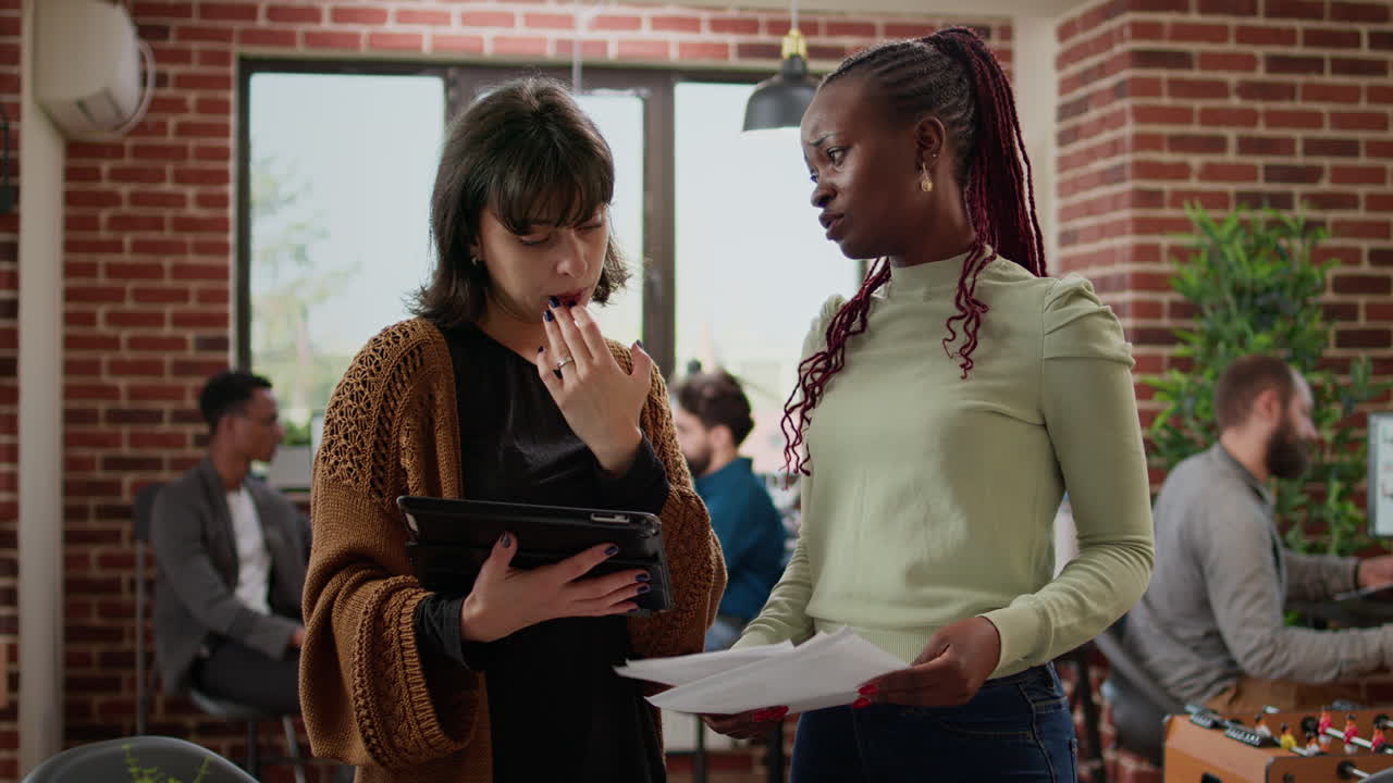 Business women analyzing information on papers and digital tablet