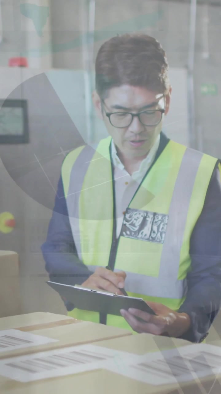 Hombre asiático con chaleco de seguridad revisando el inventario del almacén con superposición de datos