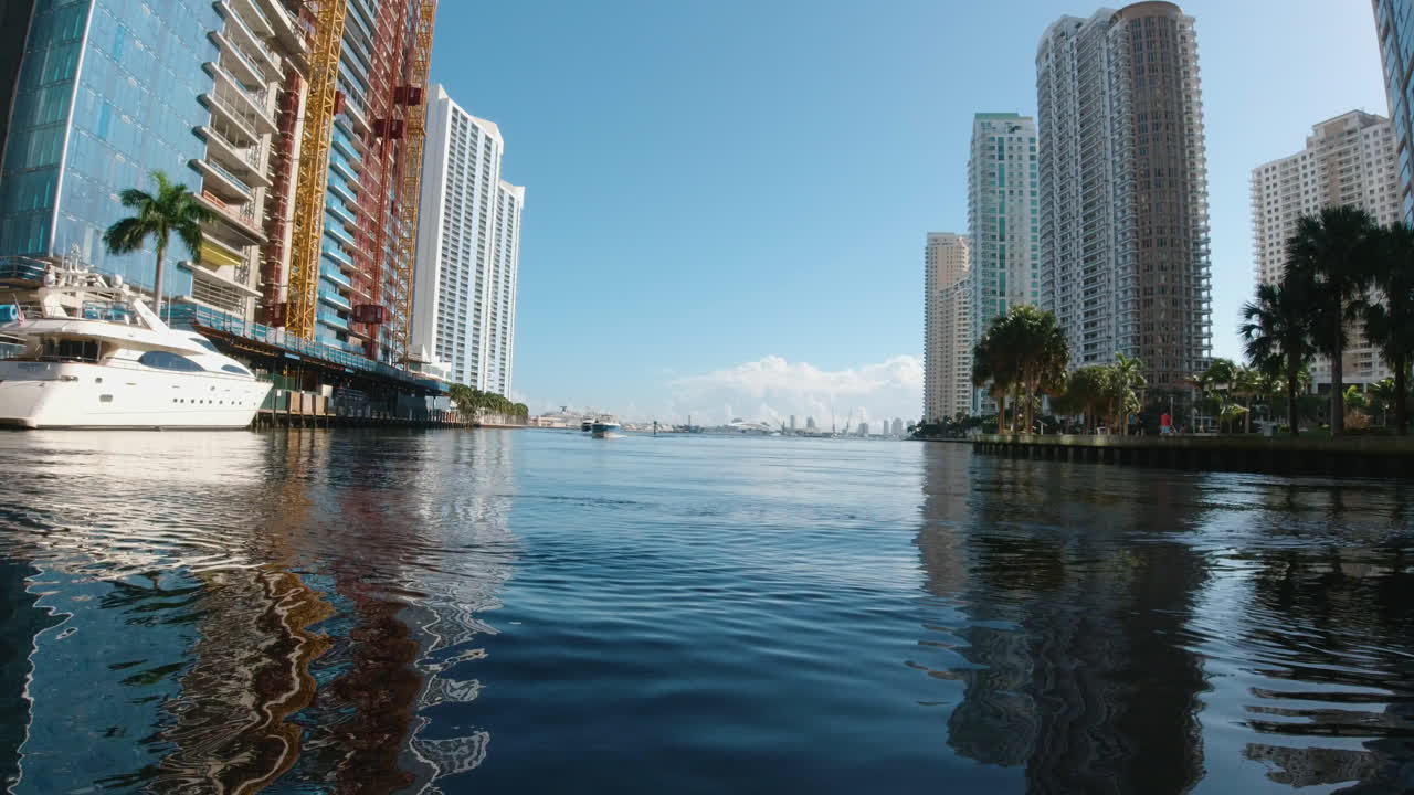 vista desde una pequeña embarcación mientras pasa por yates atracados en una estrecha vía fluvial cerca de miami, florida, mientras los edificios coloridos bordean el canal