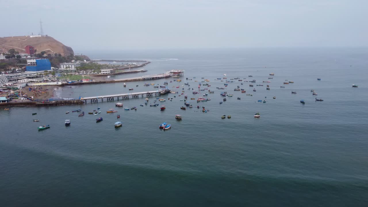 imágenes de drones, volando hacia adelante desde la playa hacia un puerto con muchos barcos de pesca y 2 muelles