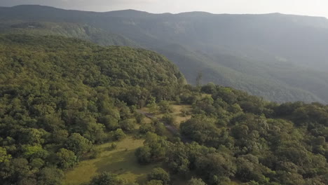 una motocicleta solitaria aparece descendiendo de una montaña verde y exuberante aérea