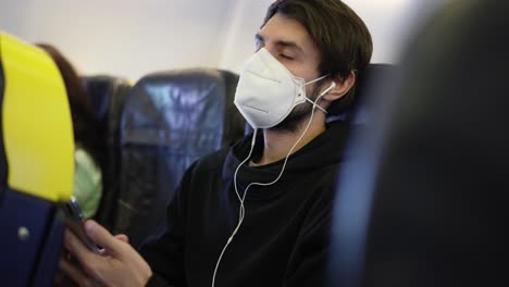 viajero en el avión con máscara poniendo auriculares para escuchar la música