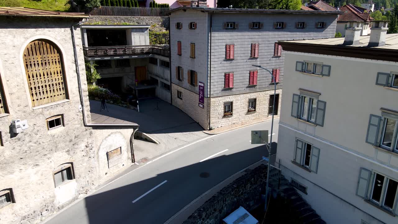 Inquadratura drone dall'alto al basso che rivela l'esterno dell'edificio di produzione nel villaggio alpino di Surava