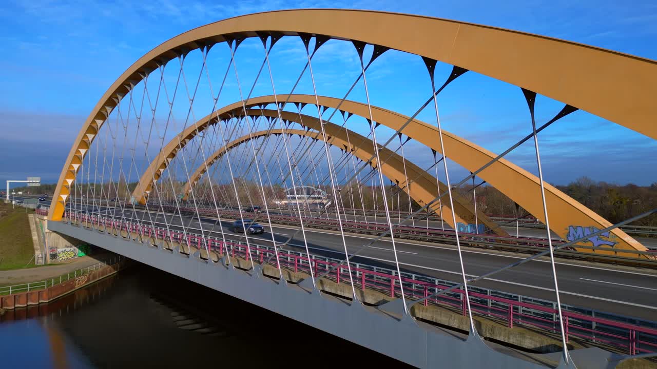 Arch bridge carrying a highway over a canal with cars moving, showcasing infrastructure and transportation in germany. Magic aerial view static panorama hovering drone