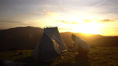 un joven está montando una tienda en la soledad de la naturaleza al atardecer después de una caminata