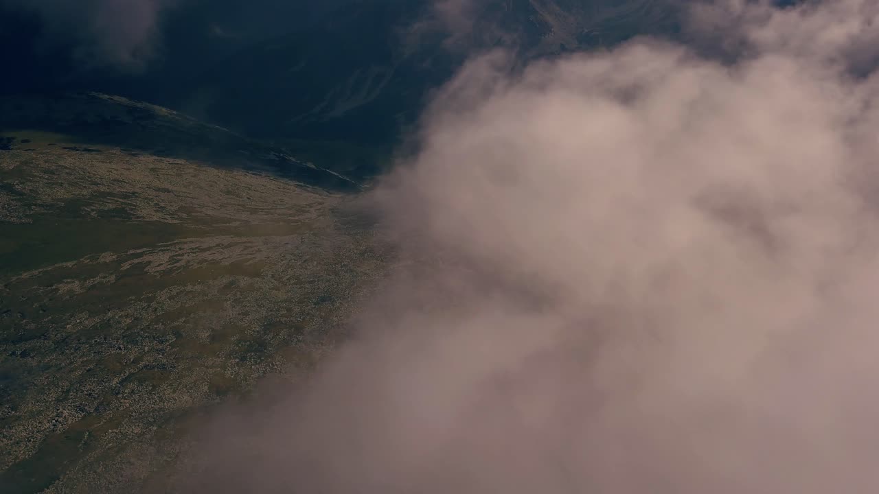 volando a través de las nubes con las montañas debajo