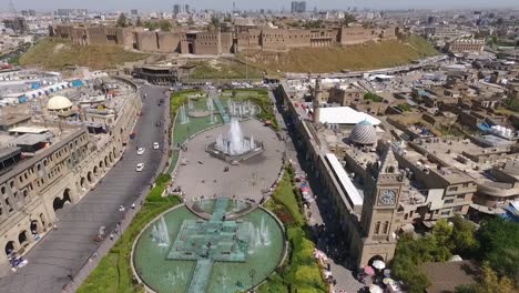 an aerial shot of the city of erbil showing the ancient erbil citadel and the garden opposite the castle with water fountains and the popular market