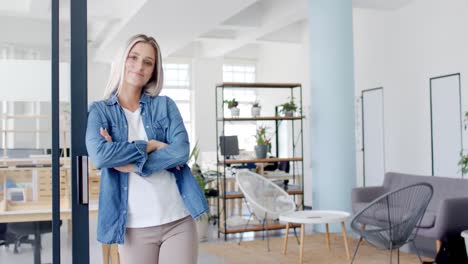 portrait of happy caucasian businesswoman with arms crossed in office in slow motion