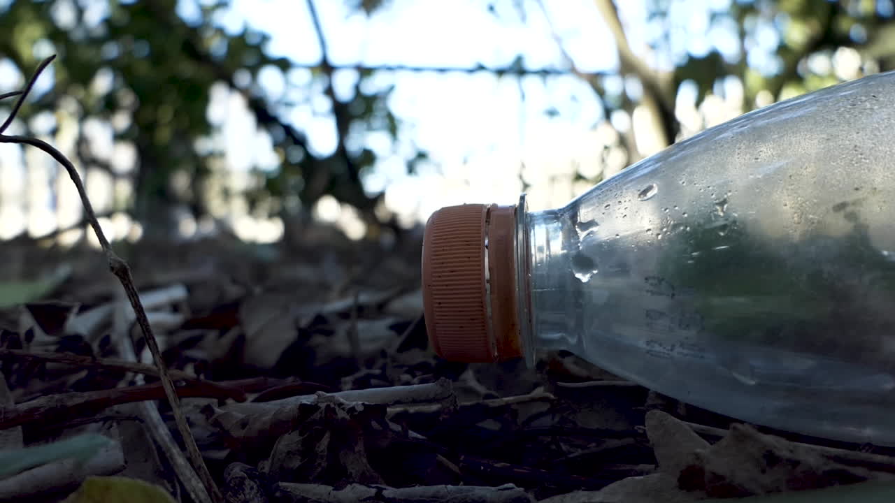 primer plano, parte superior de una botella de plástico vacía tirada o desechada en un jardín, camino con rebabas en el fondo