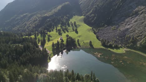 fly over a beautiful lake in obersee nafels in glarious natural region surrounded by pine tree forest in a wonderful amazing sunset time the water surface reflects the sun shine scenic travel lodge