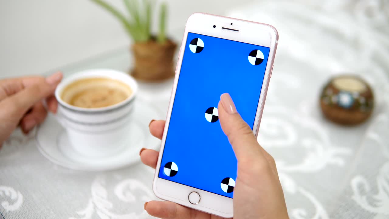 Giovane donna che tiene in mano il telefono e scorre verso l'alto con una tazza di caffè. (Schermo blu)