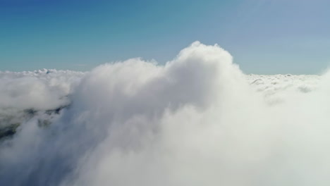 slow aerial flight through and above white dense clouds with lighting sunlight