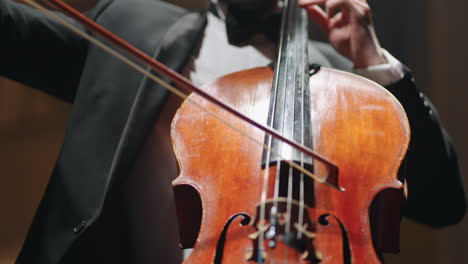 violoncellist is playing cello in philharmonic hall concert of classical music closeup view on hands with bow