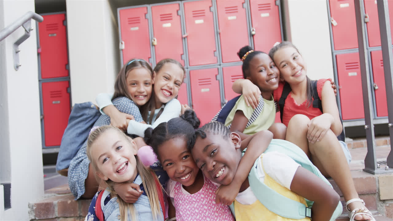 retrato de niñas felices y diversas que se abrazan en los armarios de la escuela en la escuela primaria