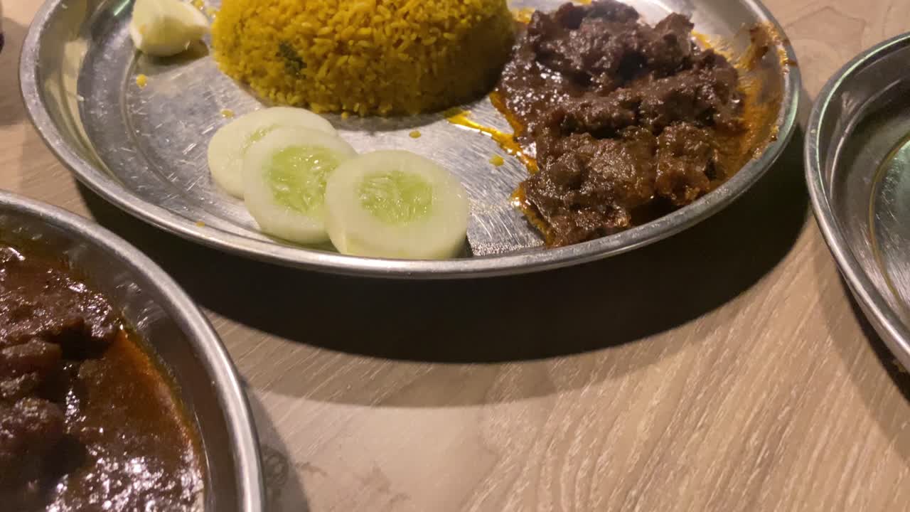 arroz pilaf con curry de carne y pepino fresco en rodajas sobre placa de metal