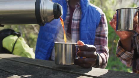 Diverse-couple-drinking-tea-and-hiking-in-countryside